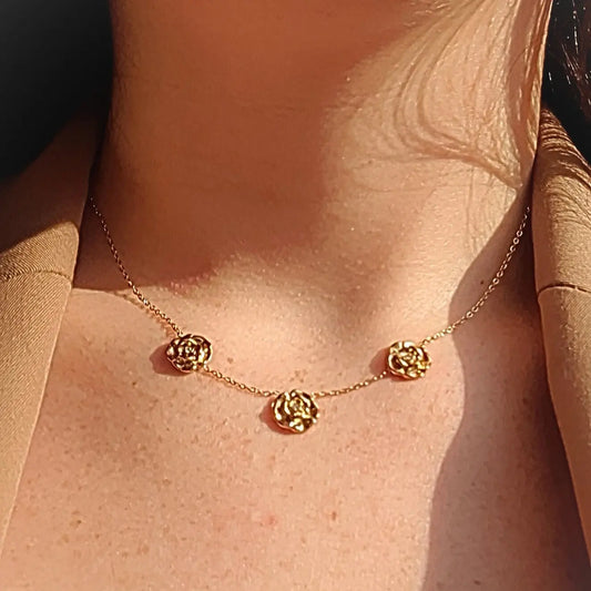 Collier en acier inoxydable en fine chaine dorée ajustable, ornée de 3 fleurs roses avec une petite pierre de zircons, style nature et élégance.
