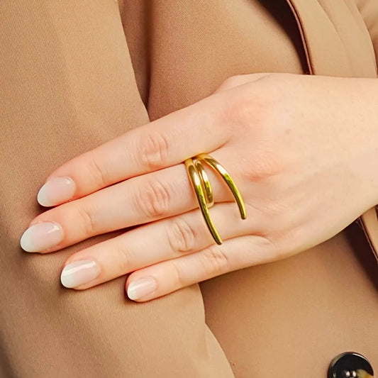 Bague en acier inoxydable doré au design moderne, composée de lignes fluides et organiques qui s’entrelacent avec élégance. 