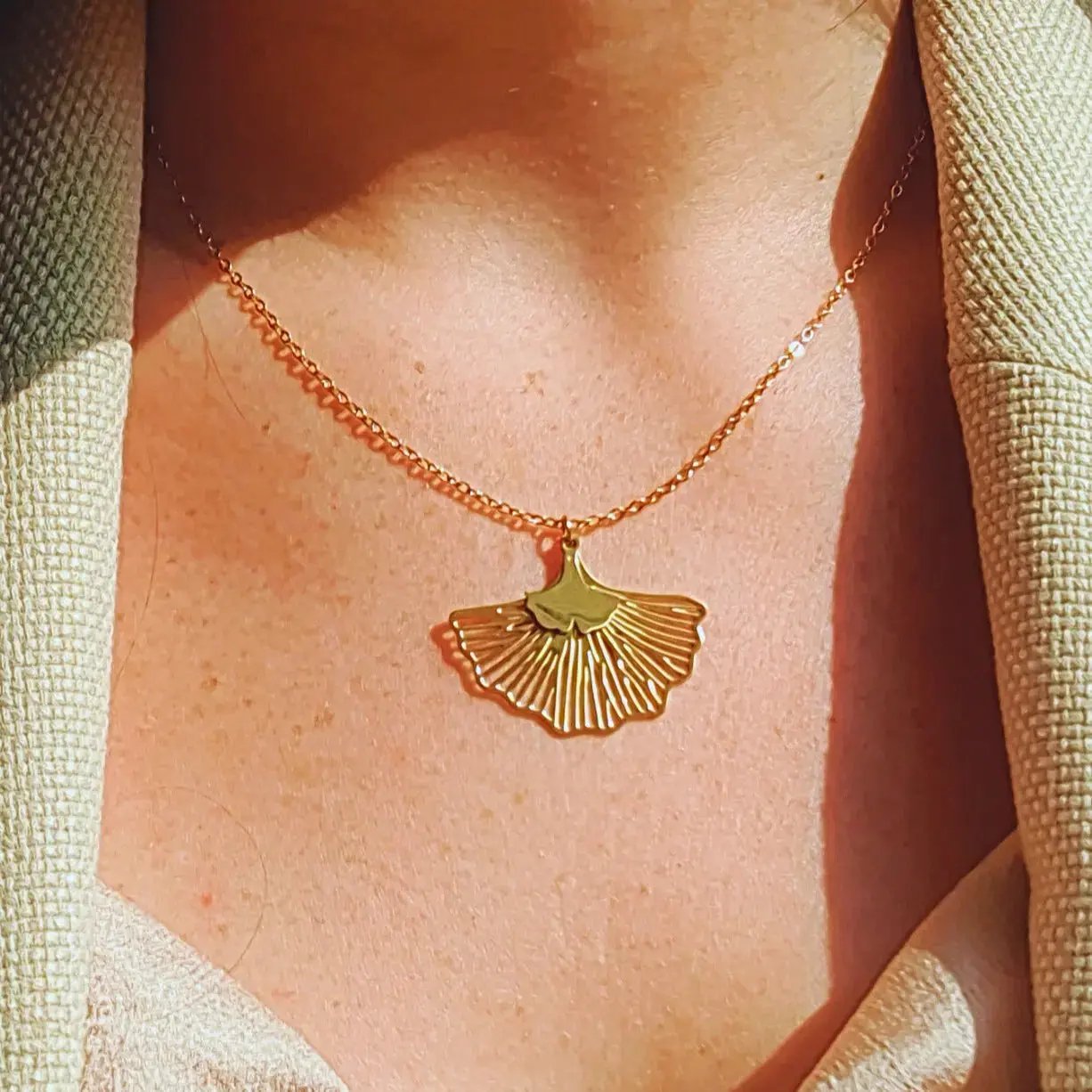 Collier doré en acier inoxydable avec deux pendentifs en fleurs de ginko ajourées et chaîne fine, réglable.