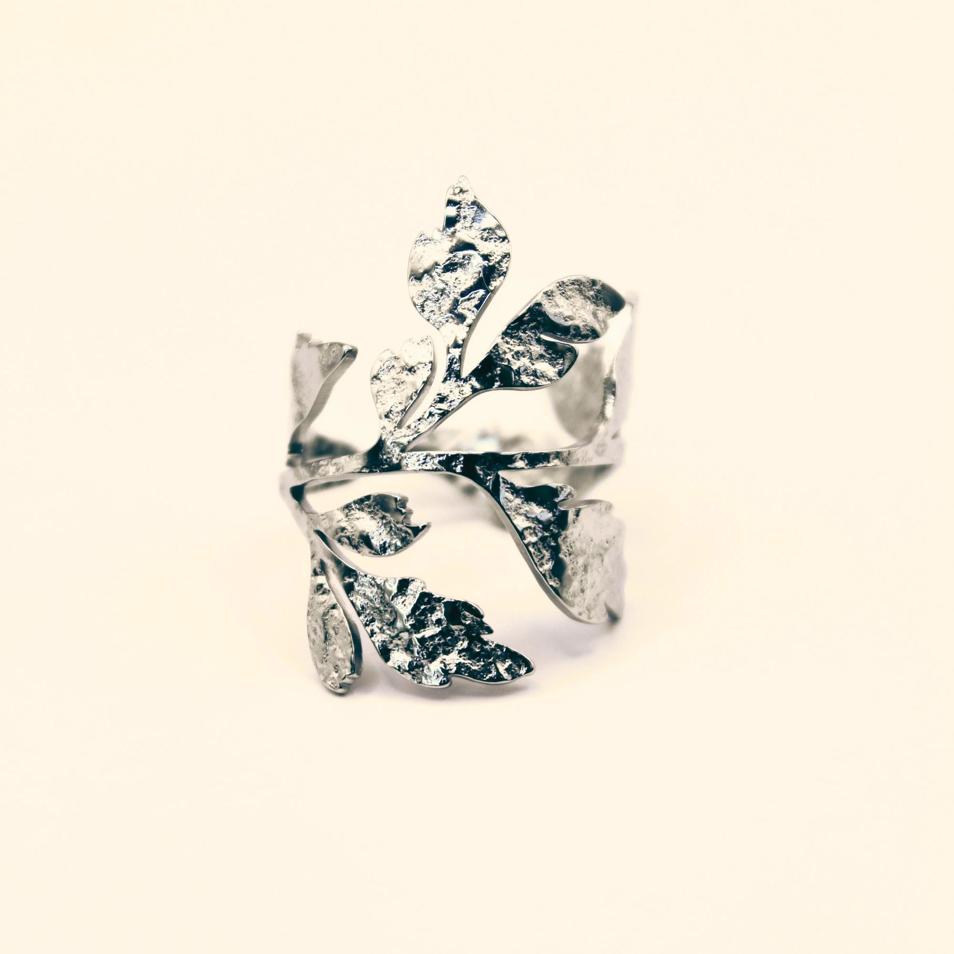 Bague en acier inoxydable argenté ajourée et ajustable, ornée de motifs de feuilles végétales texturées, style nature et élégance.