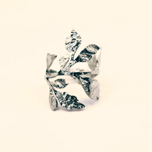 Bague en acier inoxydable argenté ajourée et ajustable, ornée de motifs de feuilles végétales texturées, style nature et élégance.