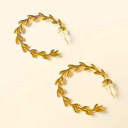 Paire de boucles d’oreilles créoles en acier inoxydable doré, ornées de motifs de feuilles façon couronne de laurier.