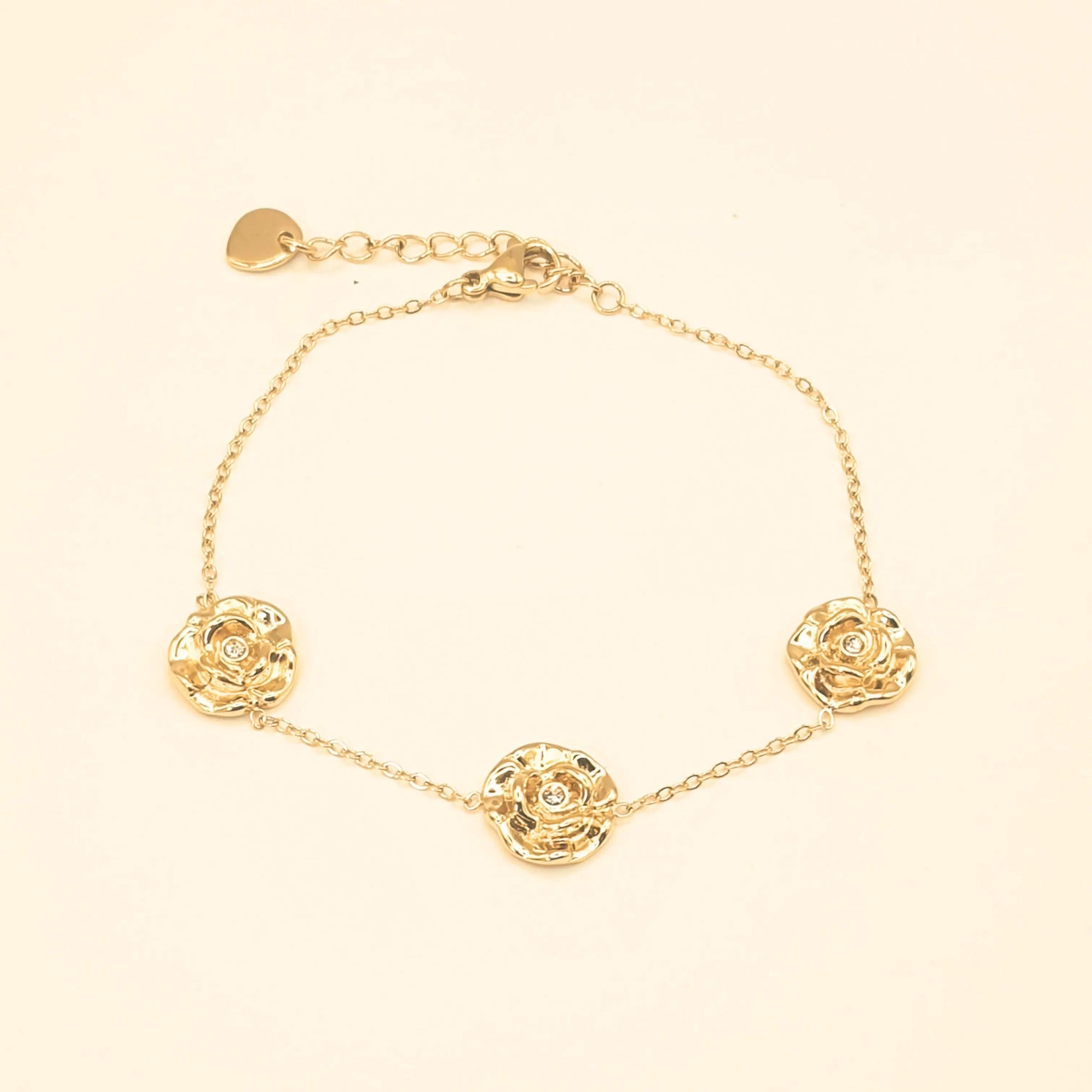 Bracelet doré en acier inoxydable avec trois pendentifs roses ajourées et chaîne fine, réglable, assorti à un collier du même design. Éclosia Bijoux